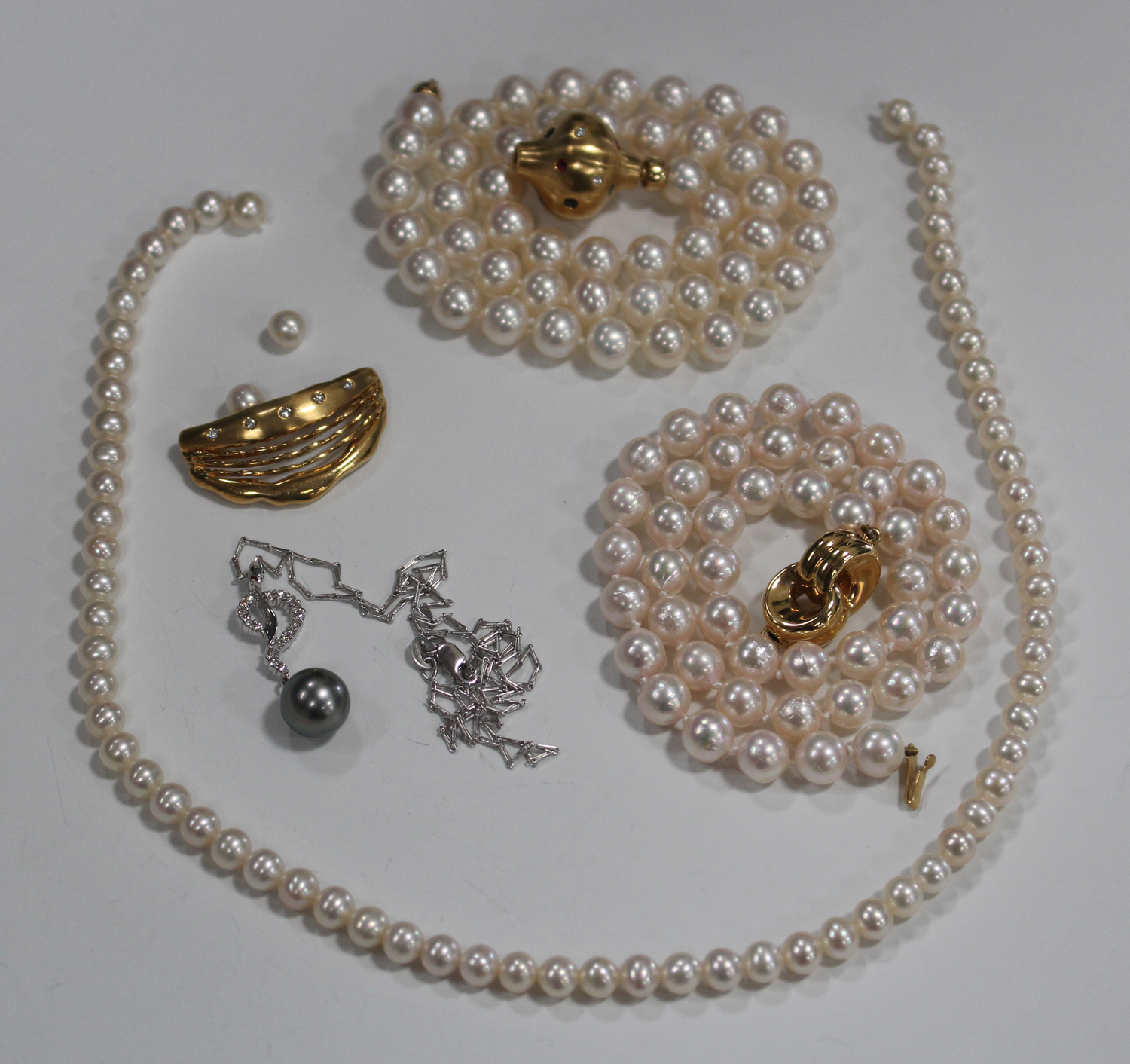 A single row necklace of uniform cultured pearls, on a gold, diamond ...
