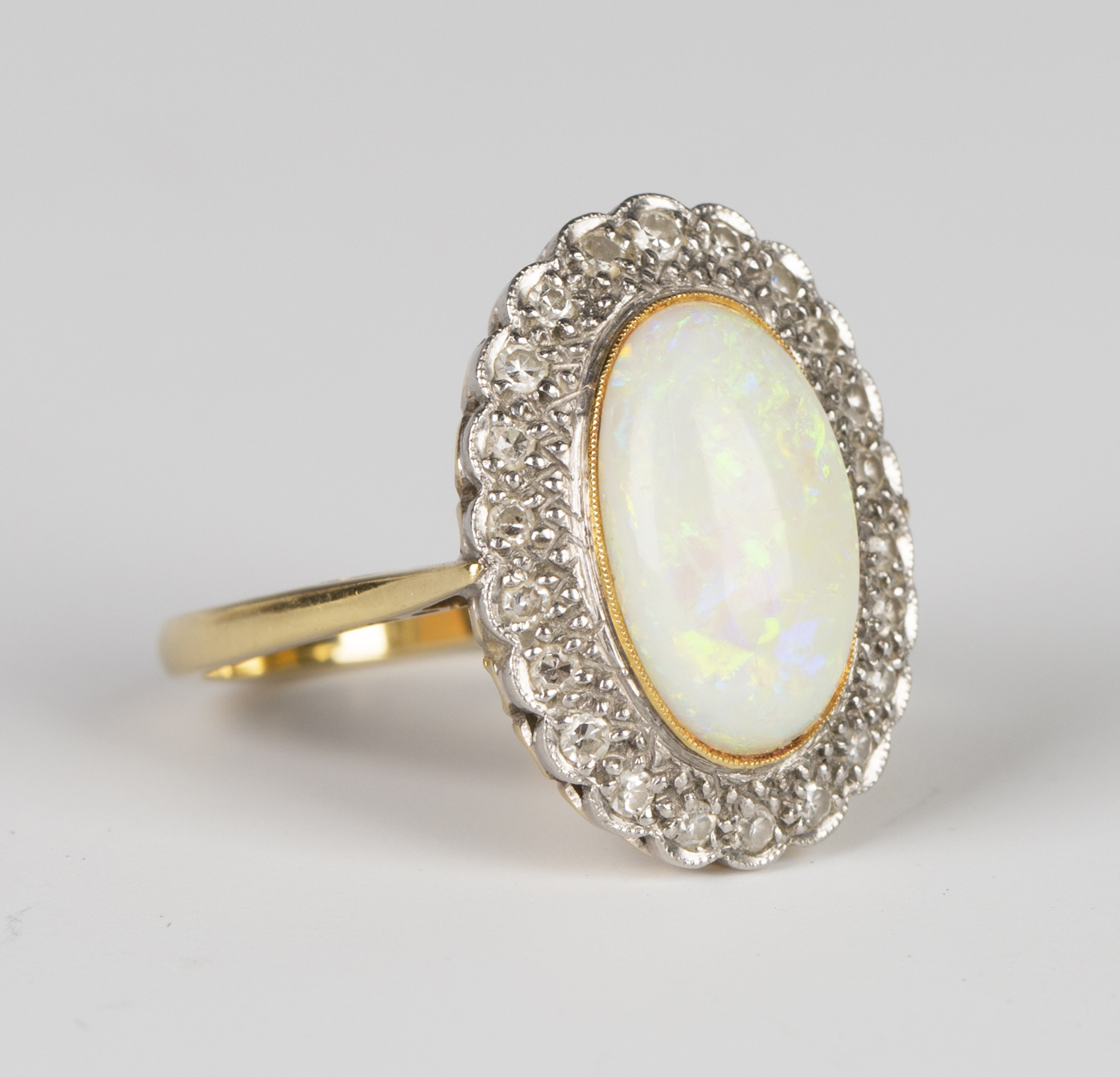 A gold, opal and diamond oval cluster ring, collet set with the oval ...