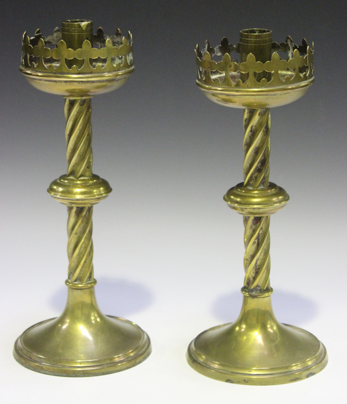 A pair of late 19th century Gothic Revival brass candlesticks with pierced  circlet tops and spiral f