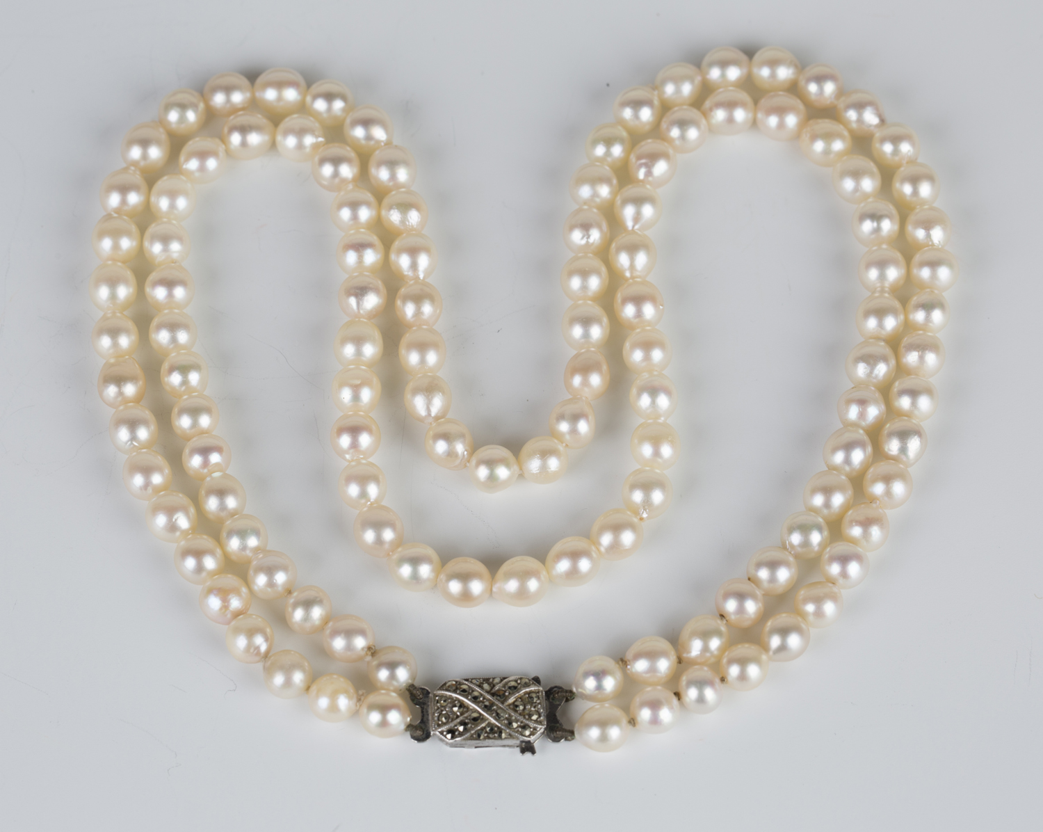 A two row necklace of uniform cultured pearls on a silver and marcasite ...