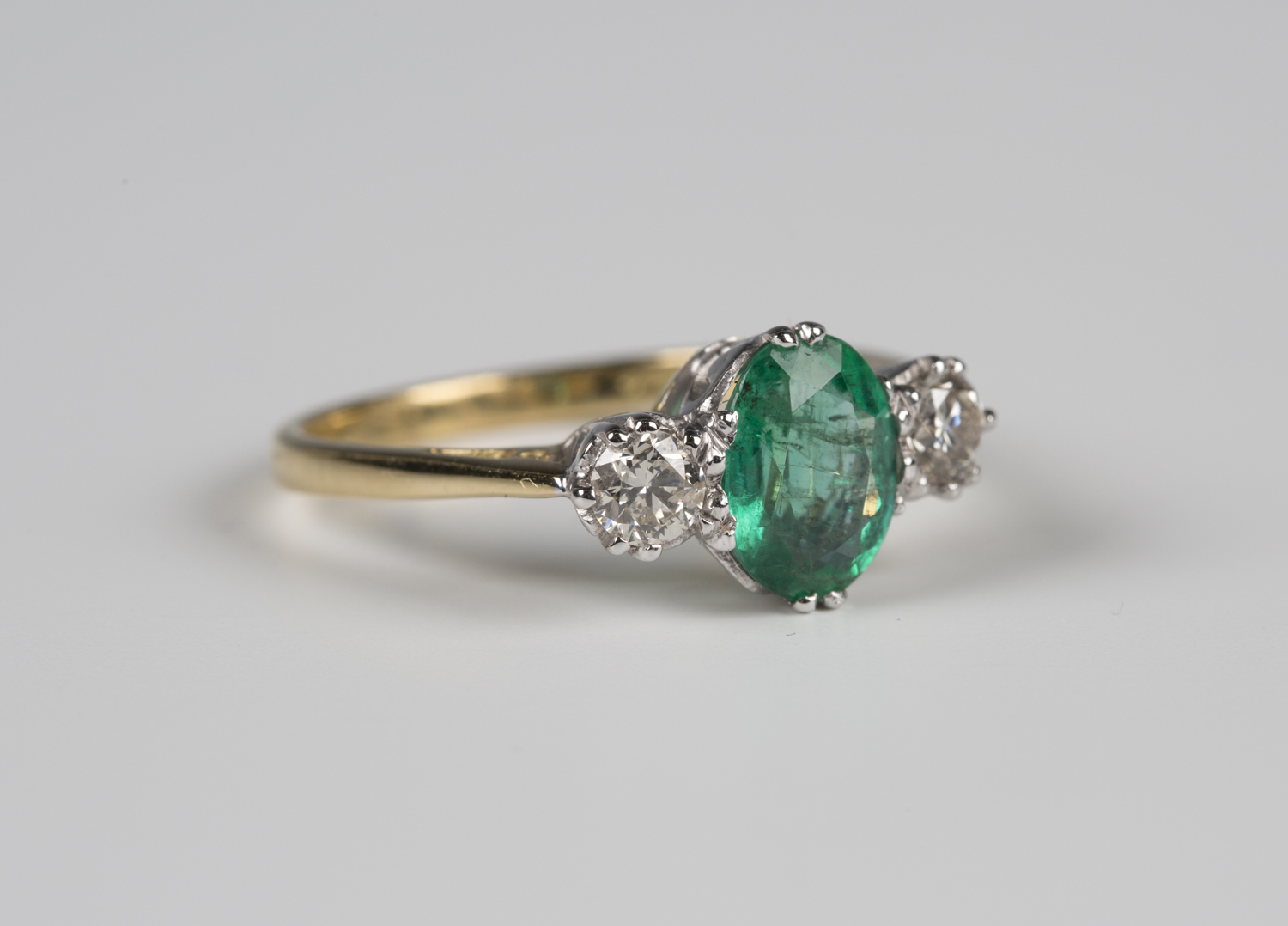 An 18ct gold, emerald and diamond three stone ring, claw set with an ...