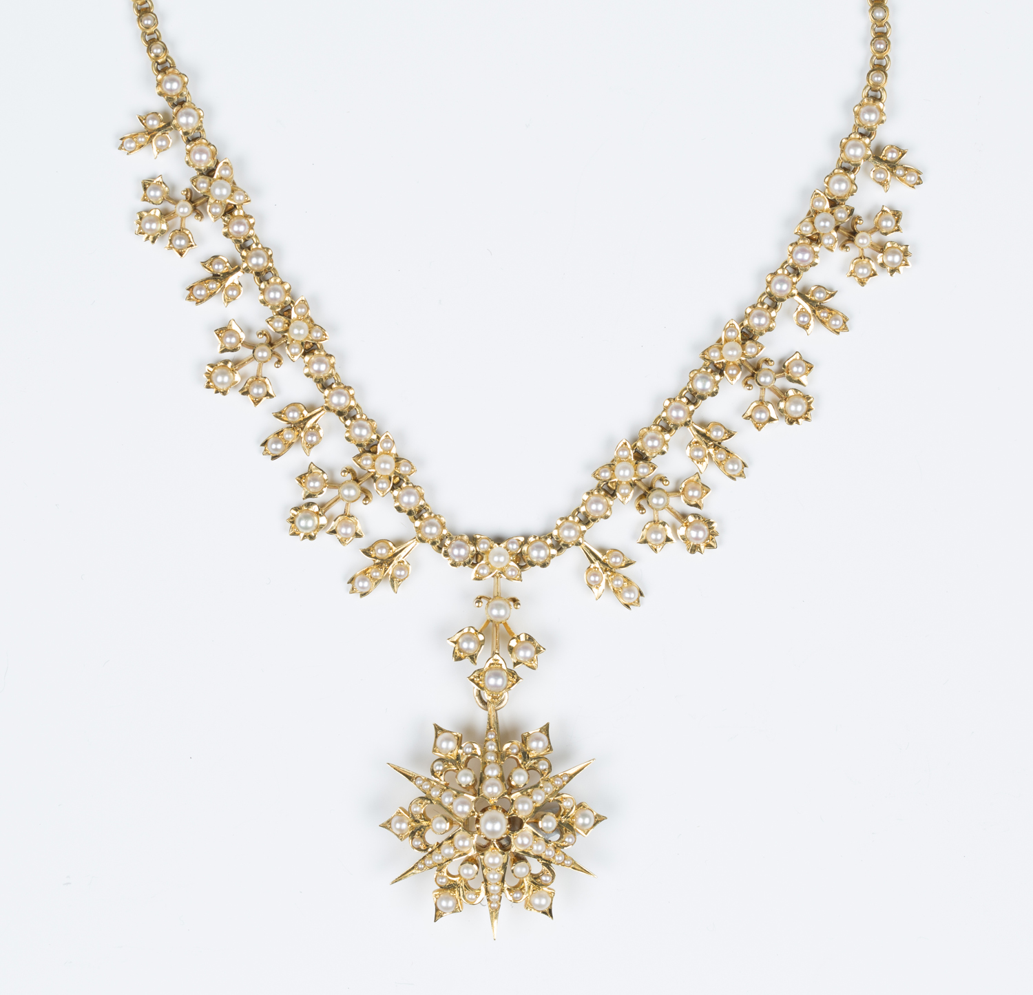 A gold and half-pearl set collar necklace, circa 1900, formed as a row ...