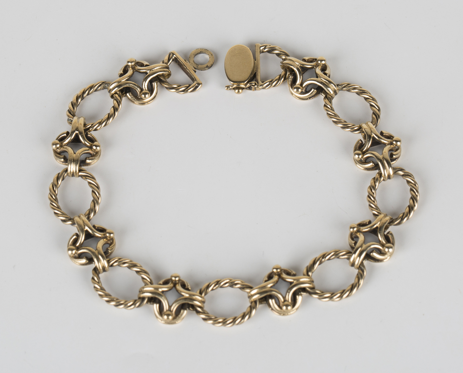 A 9ct gold bracelet in a ropetwist oval and openwork link design with a ...