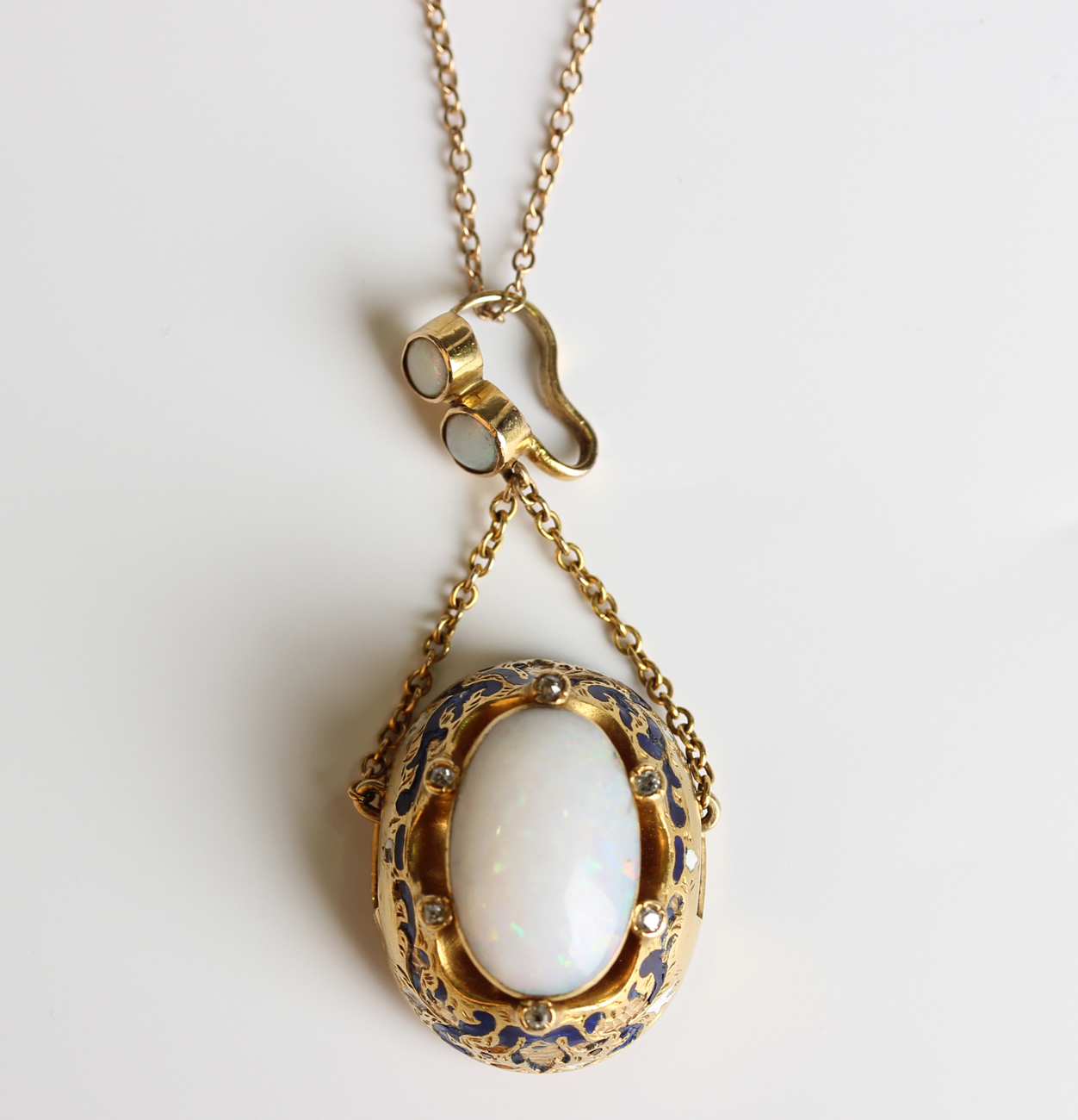 A gold, opal, diamond and enamelled oval pendant, collet set with the ...