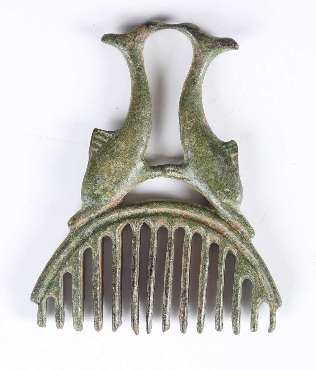 A Roman patinated bronze comb, the twin dolphin handle supporting an ...